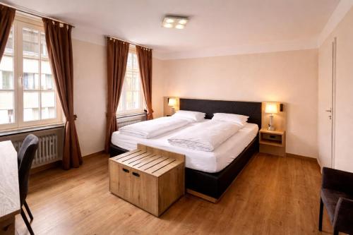 a bedroom with a large bed and two windows at Stadthotel Jülich in Jülich
