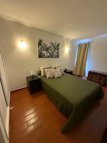 a bedroom with a green bed with two pillows at Apartamento Oura - Albufeira in Bicas