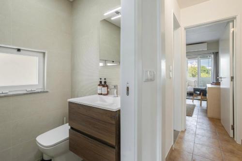 a bathroom with a sink and a toilet and a window at Centralgarve - Amazing Apt in the Heart of Vilamoura in Vilamoura