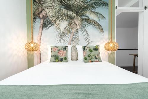a white bed with three pillows and palm trees at Unmei by LovelyStay in Caniço