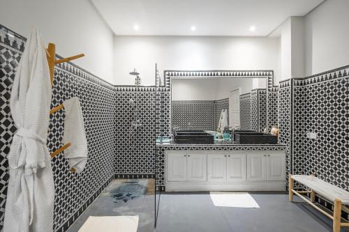 a bathroom with black and white tiled walls and a mirror at Villa Socar - Heated pool - Padel - Marrakech in Najem