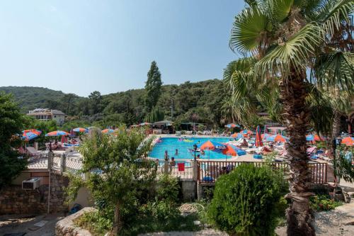 a resort with a swimming pool with people and umbrellas at Club Pink Palace Hotel in Oludeniz