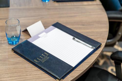 a book on a table with a pen and a glass at Daresbury Park Hotel in Daresbury