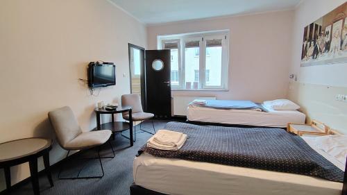 a room with two beds and a table and a tv at Pentagos in Poznań