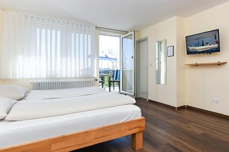 a bedroom with two beds and a large window at Pension Sielmöwe in Neuharlingersiel