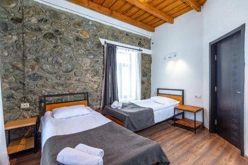 two beds in a room with a stone wall at Mestia HOTEL AMIRANI in Mestia