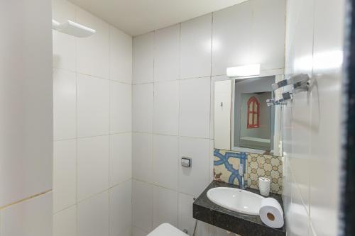 a white bathroom with a sink and a mirror at Casa da Matriz in Pirenópolis