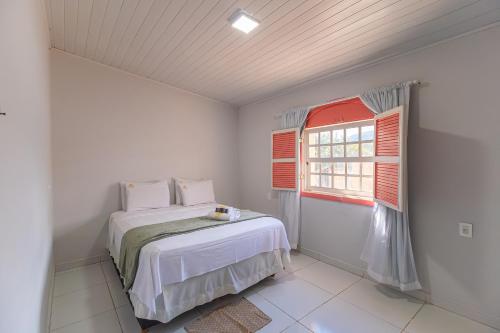 a white bedroom with a bed and a window at Casa da Matriz in Pirenópolis