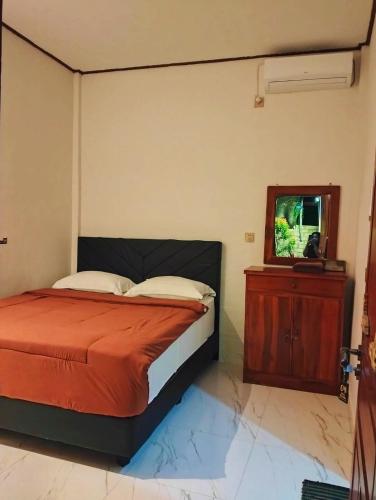 a bedroom with a bed and a dresser with a mirror at Hotel Shandira in Taliwang