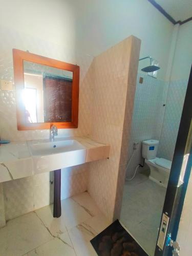 a bathroom with a sink and a mirror and a toilet at Hotel Shandira in Taliwang