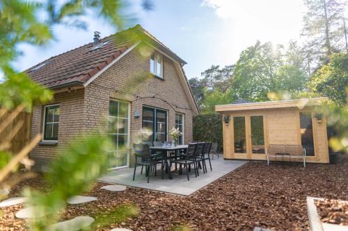 a house with a patio with a table and chairs at Luxe wellnesshuis op de Veluwe in Lunteren