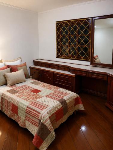 a bedroom with a bed and a dresser and a mirror at Pousada Solar Curitiba in Curitiba