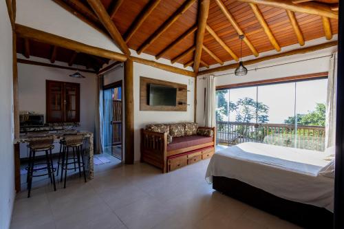 a bedroom with a bed and a balcony with a table at Siriúba Reserve in Ilhabela