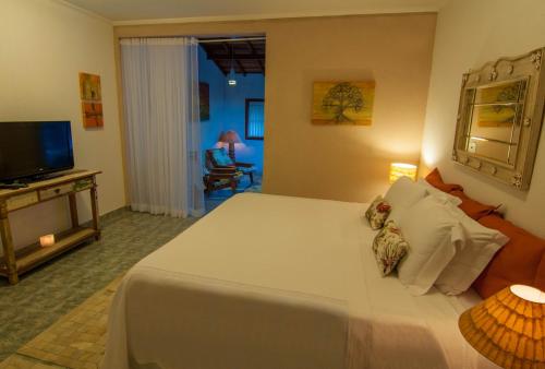 sypialnia z dużym białym łóżkiem i telewizorem w obiekcie Pousada Morada das Nuvens w mieście Monte Verde