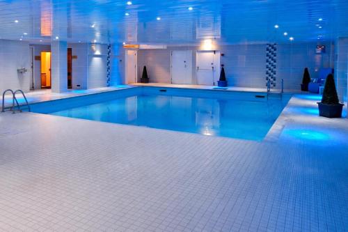 a large swimming pool with blue lighting in a building at Bury Ramsbottom Old Mill Hotel and Leisure Club in Ramsbottom