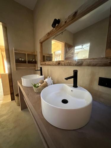 a bathroom with a white sink and two mirrors at Uroa Sunset Bliss in Uroa