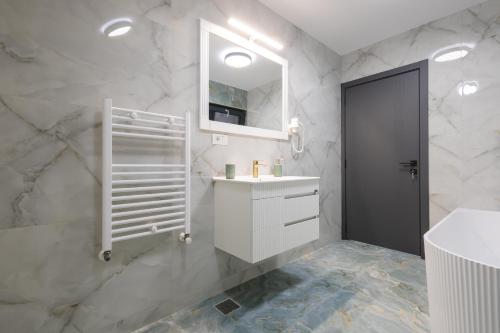 a white bathroom with a sink and a mirror at Pe Coastă in Cozăneşti