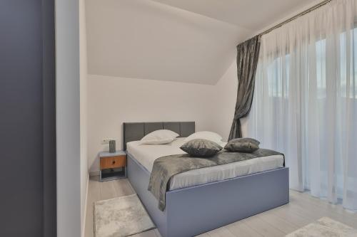 a white bedroom with a bed with a window at Pe Coastă in Cozăneşti