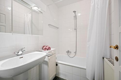 a white bathroom with a sink and a shower at Bretoenselaan 5 in De Haan