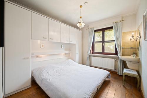 a white bedroom with a bed and a sink at Bretoenselaan 5 in De Haan