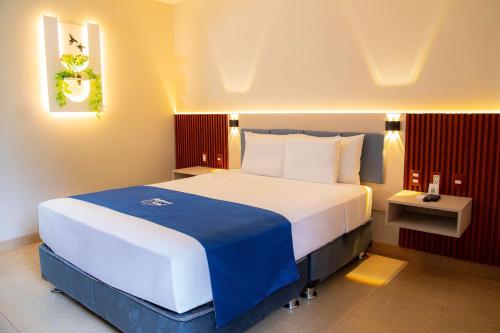 a bedroom with a large white bed with a blue blanket at Laguna Azul Hotel & Suites in Sauce