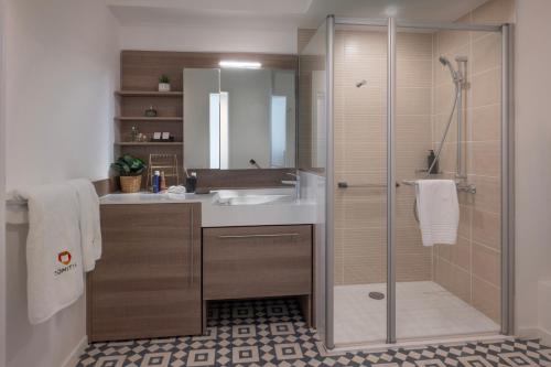 a bathroom with a glass shower and a sink at DOMITYS - Les Aviateurs in Muret
