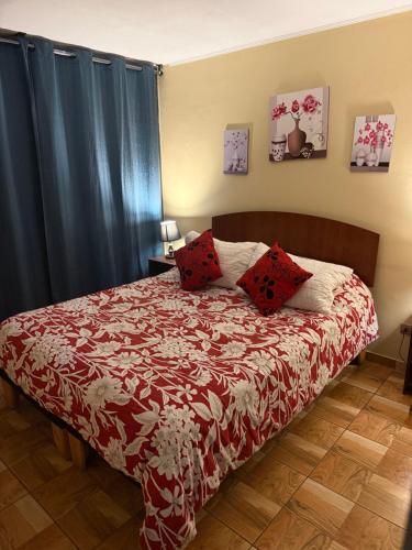 a bedroom with a bed with red pillows and blue curtains at 703 Departamento 15 minutos de Aeropuerto Maipu in Santiago