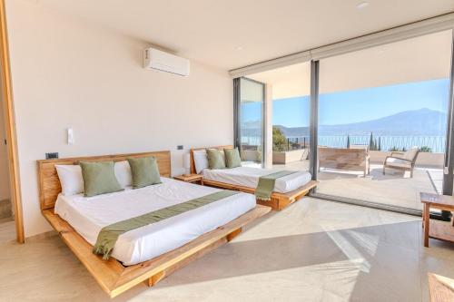 a bedroom with two beds and a large window at Casa Ambar Luxury Lake View Villa Pool Design in San Juan Cosalá