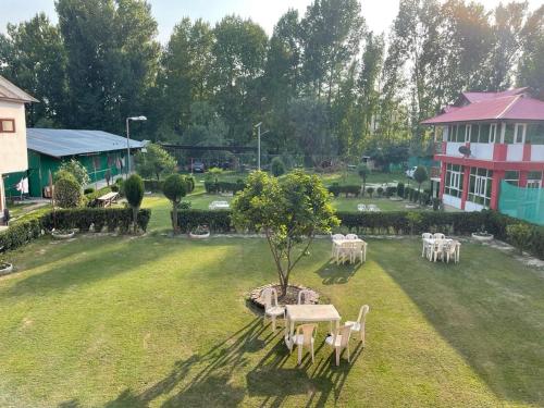 a garden with a table and chairs and a building at Hotel New Sahil - Srinagar in Srinagar