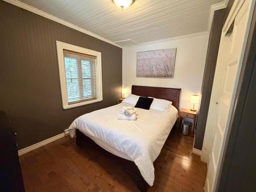a bedroom with a bed with white sheets and a window at La Suite du Havre in Saint-Charles-des-Grondines