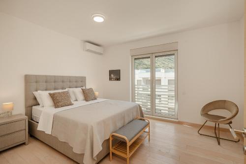 a bedroom with a bed and a chair and a window at River side apartment B17 in Herceg-Novi