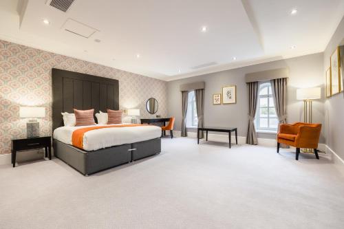 a hotel room with a bed and a desk and chairs at Vale Resort in Hensol