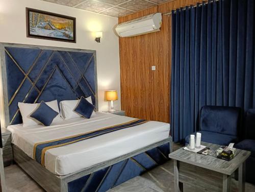 a bedroom with a large bed and a chair at Star Hotel Lahore in Lahore
