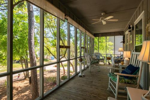 a screened porch with windows and a ceiling fan at Beaching & Griping by Oak Island Accommodations in Oak Island