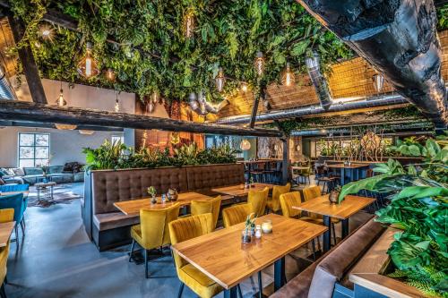 a restaurant with wooden tables and chairs and plants at Summio Vakantiepark Schaijk in Schayk