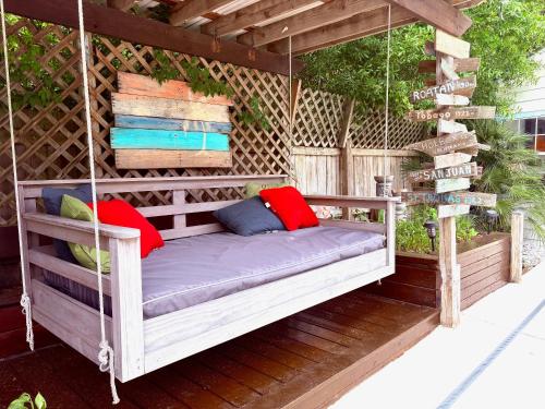 a porch swing with pillows on a patio at Romantic Beach Style Cottage close to everything! in Whitehouse Plantation