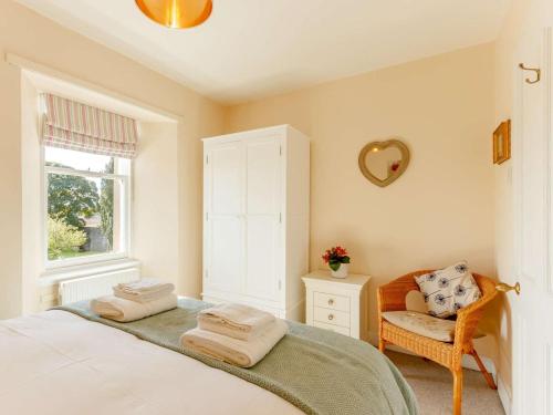a bedroom with a bed and a chair and a window at 4 Bed in Brechin oc-89698 in Brechin