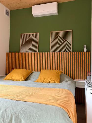 a bed with two yellow pillows and a green wall at Black Cabin Veluwe - Wellness in het bos - Airco & Sauna in Putten