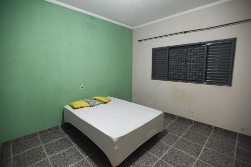 a bed in a room with a green wall at Casa com Churrasqueira e WiFi em Parque Ribeirao in Ribeirão Preto