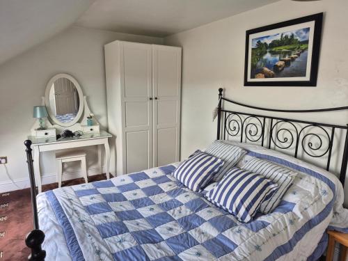 a bedroom with a bed with striped pillows and a mirror at Coast to Coast Accom - Shap in Shap