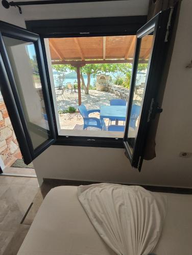 a room with a window with a table and a chair at John's Guesthouse in Ksamil