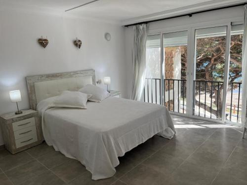 a white bedroom with a bed and a balcony at Volver in Mijas Costa