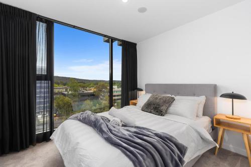 a bedroom with two beds and a large window at The Piastri at Midnight in Braddon