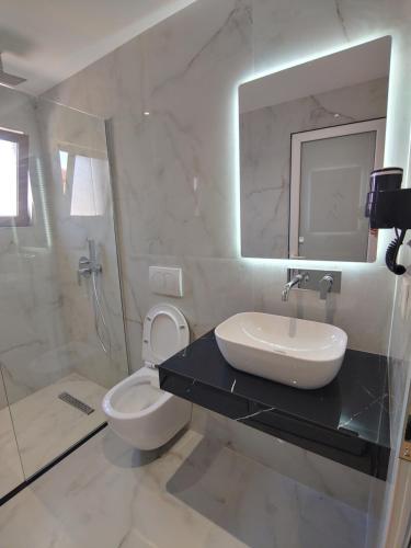 a bathroom with a sink and a toilet and a mirror at Villa LeoZeka in Ksamil