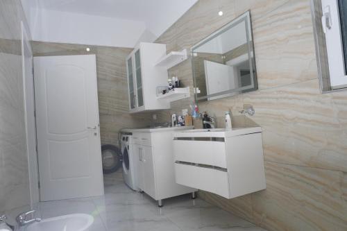 a white bathroom with a sink and a mirror at Vila Kabashi in Korçë