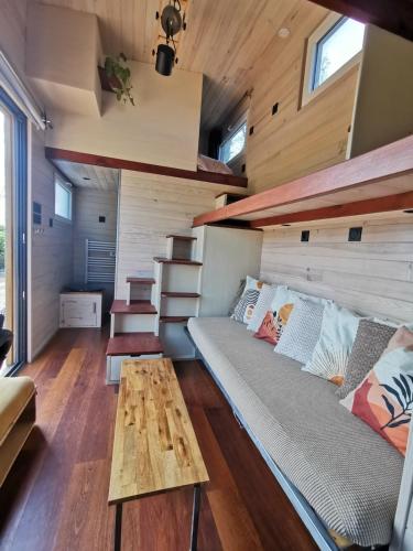 a tiny house with a couch and a table at La Tiny des Prés in LʼAbsie