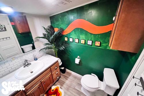 a bathroom with a toilet and a green wall at The Shack at Long Beach - A Psychedelic Getaway in Long Beach