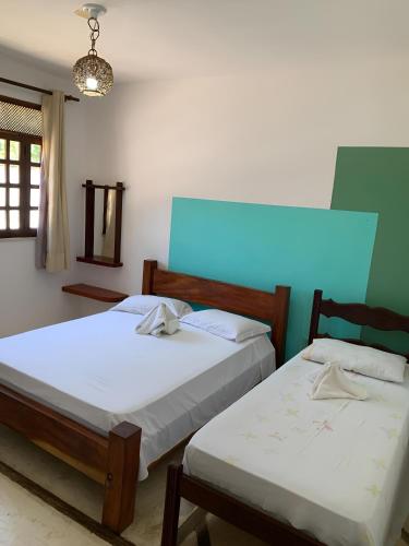 a bedroom with two beds and a light on the wall at Pousada PauBrasil in Barra Grande