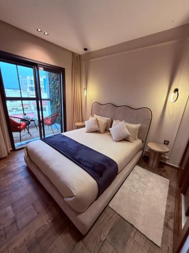 a bedroom with a large bed and a large window at Votre escapade d été à deux pas de la plage in Kenitra