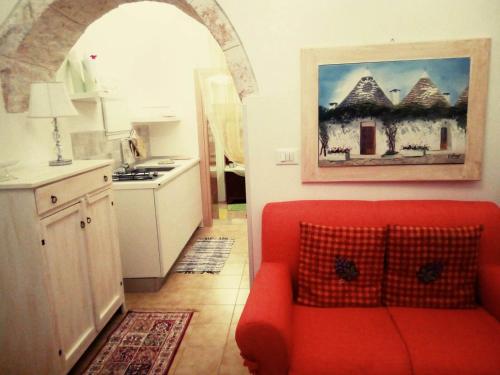 uma sala de estar com um sofá vermelho numa cozinha em Trullo Sereno Angelo em Locorotondo